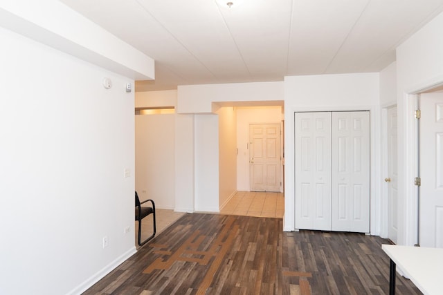 unfurnished bedroom featuring dark wood-type flooring, a closet, and baseboards