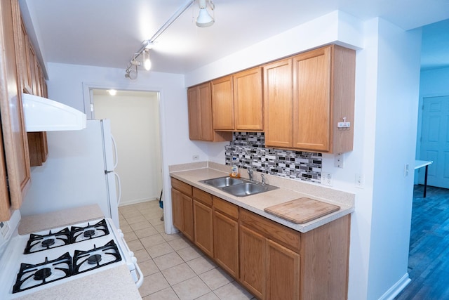 kitchen with white appliances, a sink, light countertops, backsplash, and light tile patterned flooring