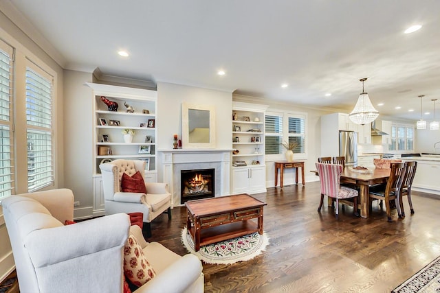 living area with a lit fireplace, ornamental molding, dark wood finished floors, and a wealth of natural light