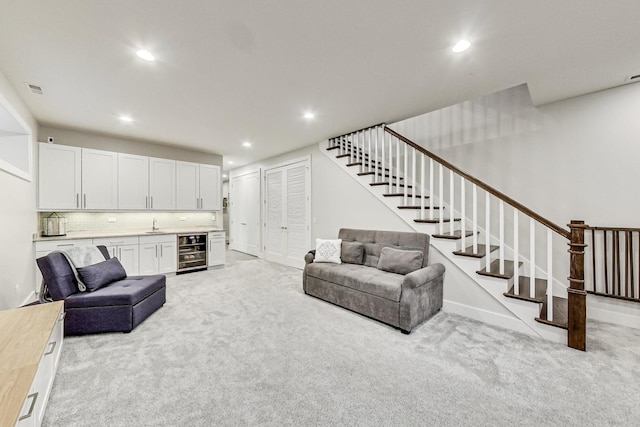 living area featuring light colored carpet, wine cooler, stairs, indoor wet bar, and recessed lighting