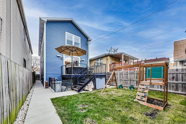 back of property featuring a deck, stairway, a fenced backyard, and a lawn