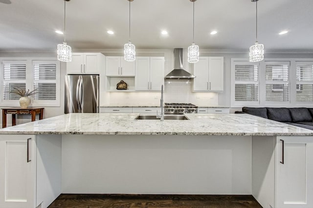 kitchen with a spacious island, freestanding refrigerator, white cabinetry, a sink, and wall chimney exhaust hood