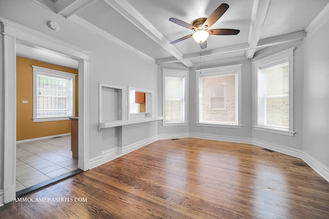 empty room featuring coffered ceiling, crown molding, baseboards, and wood finished floors