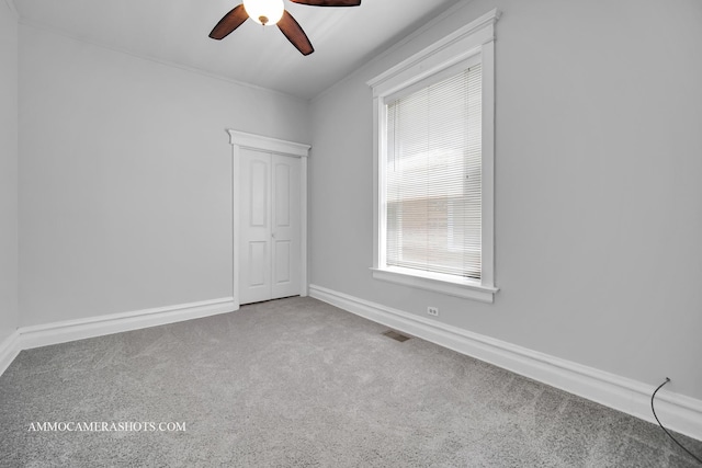 carpeted spare room featuring baseboards, visible vents, and ceiling fan