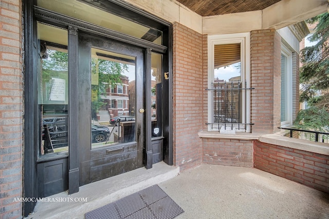 doorway to property with a porch and brick siding