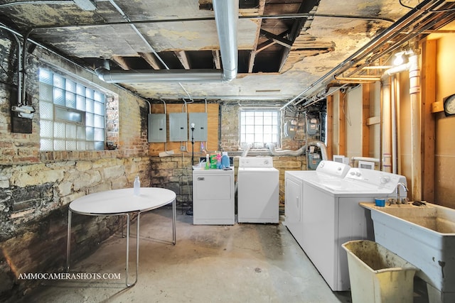 below grade area featuring electric panel, a sink, and washing machine and clothes dryer