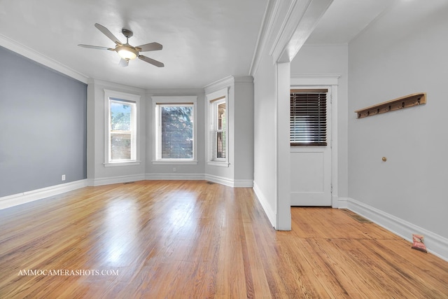 spare room featuring a ceiling fan, baseboards, crown molding, and light wood finished floors