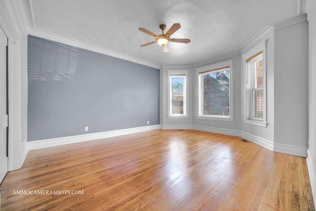 empty room featuring light wood-style floors, baseboards, visible vents, and crown molding