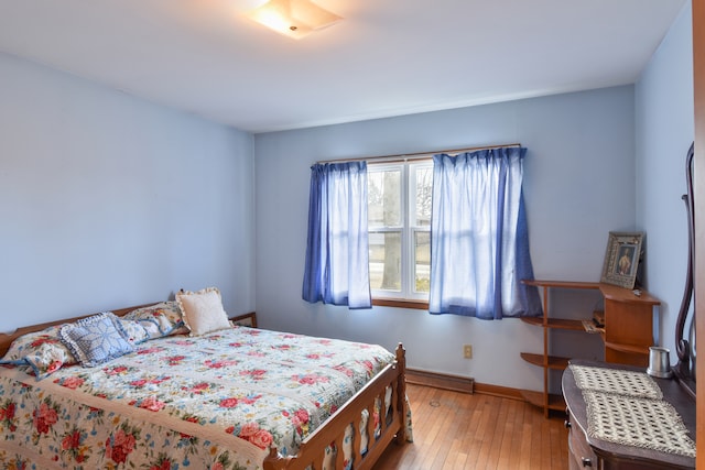 bedroom featuring baseboard heating, wood-type flooring, and baseboards