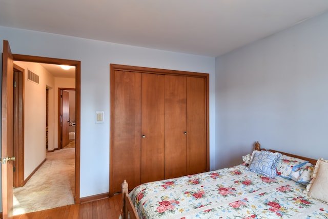 bedroom featuring light wood-style floors, baseboards, visible vents, and a closet