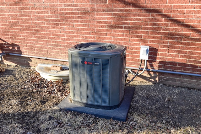 exterior details featuring cooling unit and brick siding