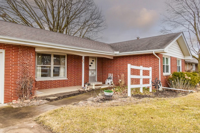 single story home featuring brick siding and roof with shingles