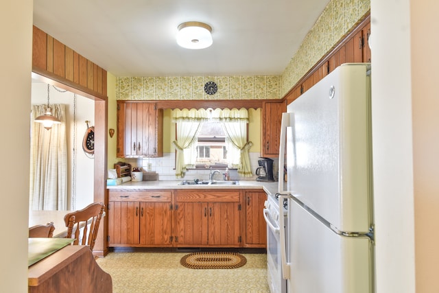 kitchen featuring white appliances, a sink, light countertops, brown cabinets, and light floors