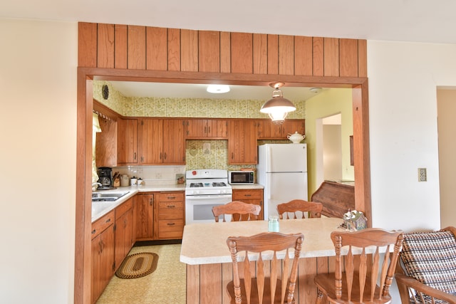 kitchen featuring white appliances, a kitchen breakfast bar, light countertops, backsplash, and light floors