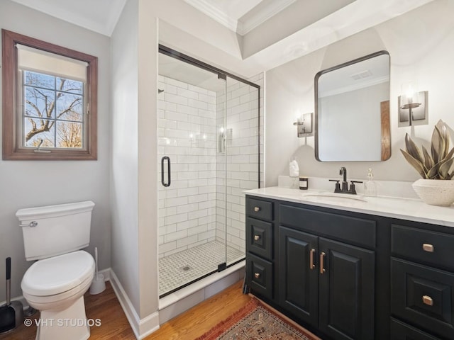 bathroom with toilet, wood finished floors, a stall shower, and ornamental molding