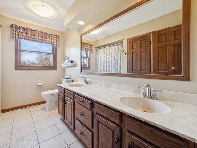 bathroom featuring a sink, baseboards, toilet, and tile patterned floors