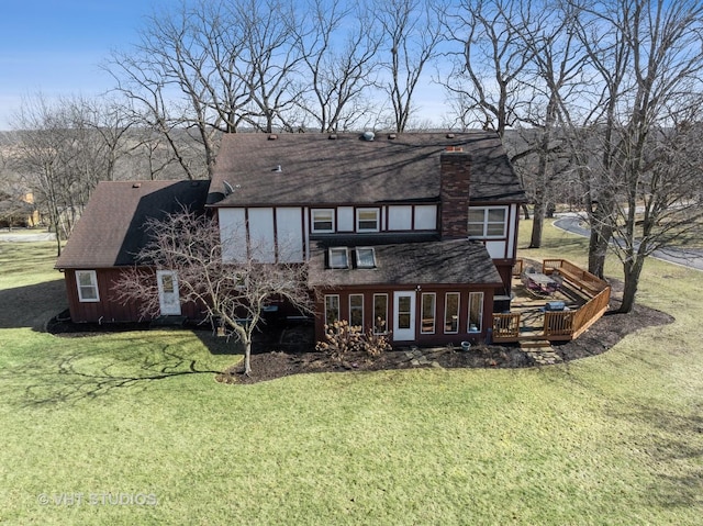 rear view of property featuring a chimney, a lawn, and a wooden deck