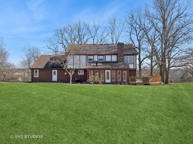 back of property with a lawn, a chimney, and a wooden deck