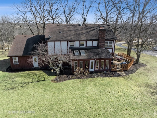 back of property featuring a deck, a lawn, and a chimney