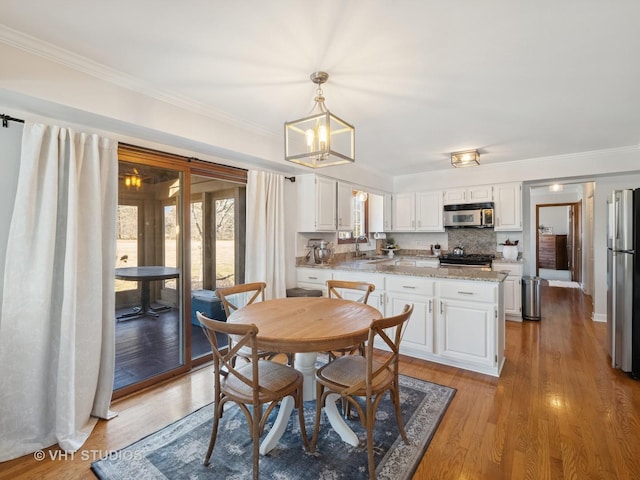 dining area featuring plenty of natural light, light wood-style floors, and ornamental molding