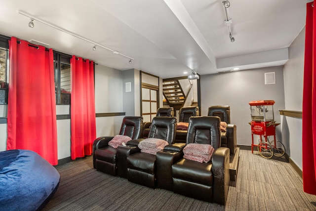 carpeted home theater room with rail lighting and baseboards