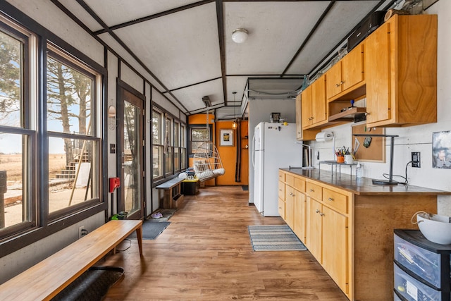 kitchen featuring light wood-type flooring, dark countertops, vaulted ceiling, and freestanding refrigerator