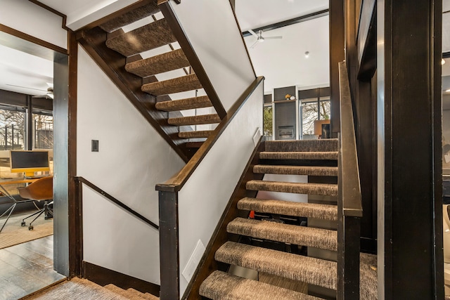 stairs with wood finished floors and a ceiling fan