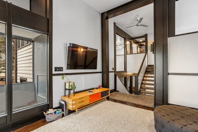 living area featuring stairs, ceiling fan, and wood finished floors