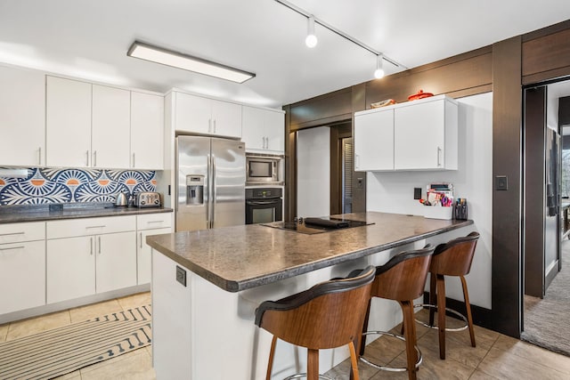 kitchen with dark countertops, light tile patterned floors, black appliances, and a kitchen bar