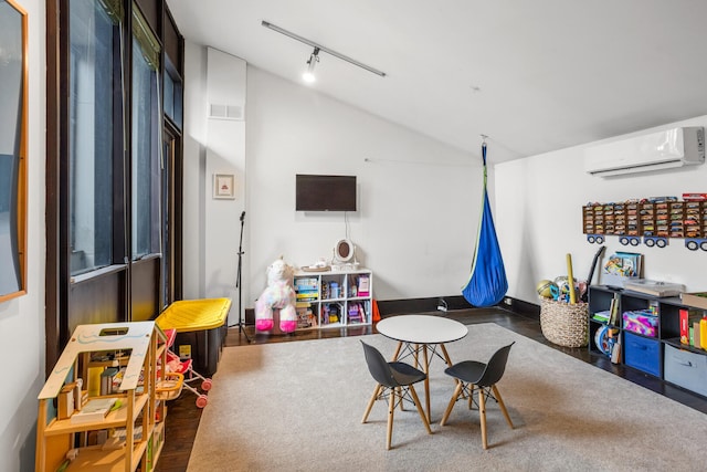 game room with wood finished floors, visible vents, lofted ceiling, rail lighting, and a wall mounted air conditioner