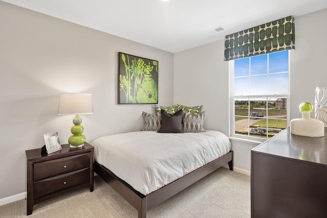 bedroom featuring baseboards, visible vents, and light colored carpet