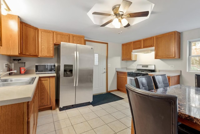 kitchen with light tile patterned floors, appliances with stainless steel finishes, ceiling fan, a sink, and under cabinet range hood