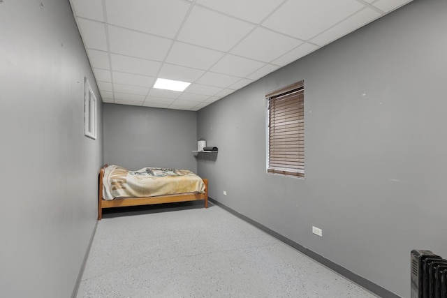 bedroom with baseboards, a paneled ceiling, and radiator