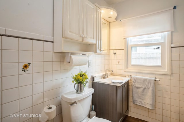 half bath with toilet, vanity, and tile walls