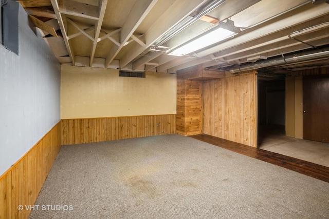 finished basement with wainscoting, wood walls, carpet, and visible vents