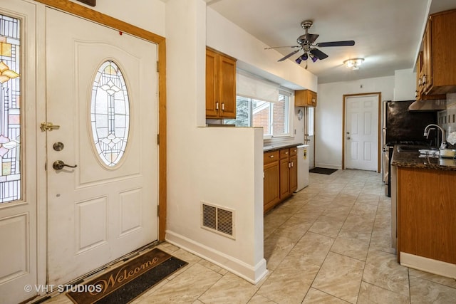 interior space featuring brown cabinets, visible vents, baseboards, and a ceiling fan