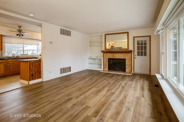 unfurnished living room featuring light wood-style floors, visible vents, and a fireplace