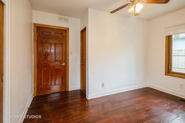 unfurnished room with ceiling fan, dark wood finished floors, visible vents, and baseboards