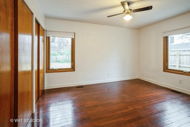 spare room with dark wood-style floors, plenty of natural light, and visible vents