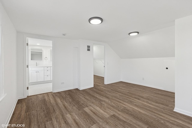 bonus room featuring dark wood-type flooring, baseboards, and lofted ceiling