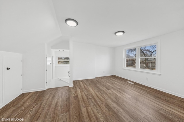 unfurnished living room with wood finished floors, baseboards, and lofted ceiling