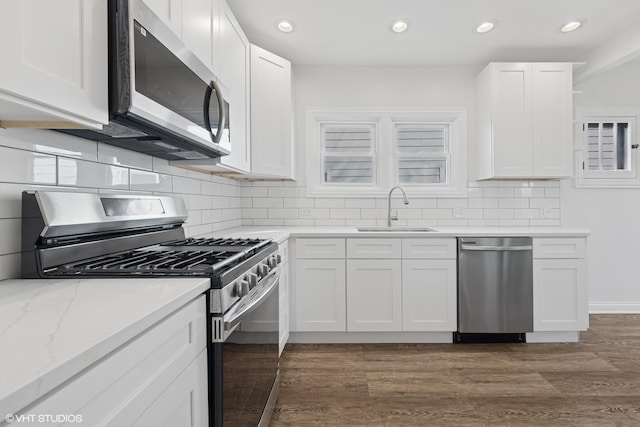 kitchen with appliances with stainless steel finishes, a sink, white cabinetry, tasteful backsplash, and recessed lighting
