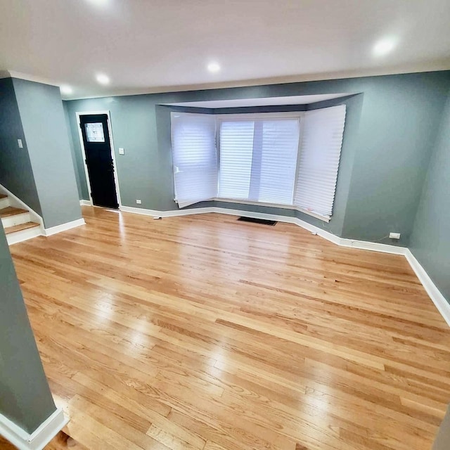 interior space with baseboards, light wood finished floors, and stairs