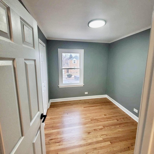 unfurnished bedroom with ornamental molding, light wood finished floors, a closet, and baseboards