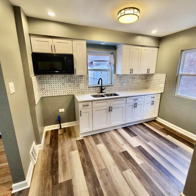 kitchen with black microwave, visible vents, a sink, and white cabinetry