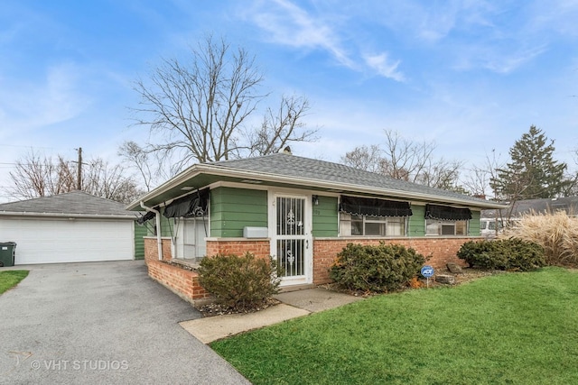 view of front facade featuring brick siding, a garage, an outbuilding, and a front yard