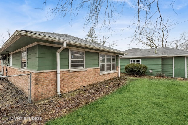 view of home's exterior with a yard, brick siding, and fence