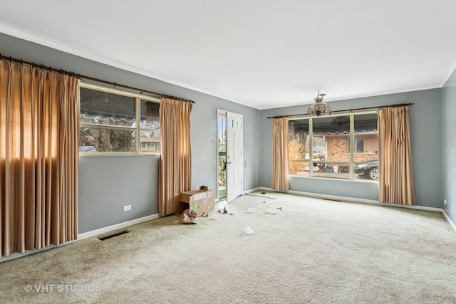 carpeted spare room featuring baseboards, visible vents, and ornamental molding