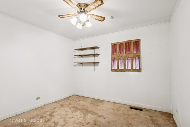 carpeted empty room with visible vents, a ceiling fan, crown molding, and baseboards