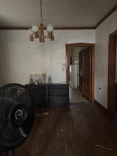 unfurnished dining area with ornamental molding, wood finished floors, and a notable chandelier